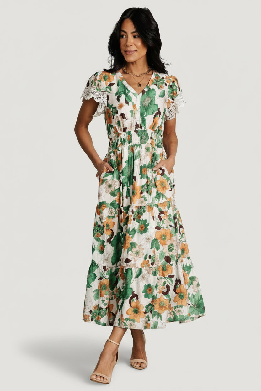 Front model view of Aliyah smocked midi dress in cream with orange and green floral print, V-neck, lace-trim short sleeves, smocked waist and pockets.