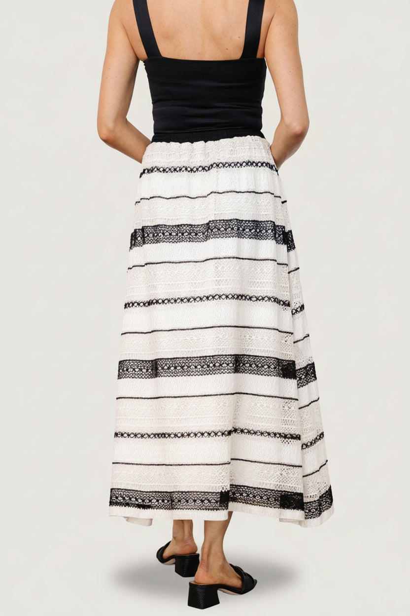 Flat-lay product image of Alondra woven skirt in cream and black, showing textured pattern, waistband, and lining.