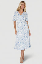 Front view of Amelie Wrap Midi Dress in blue-and-off-white floral crepe, showing flutter sleeves and midi-length hem.