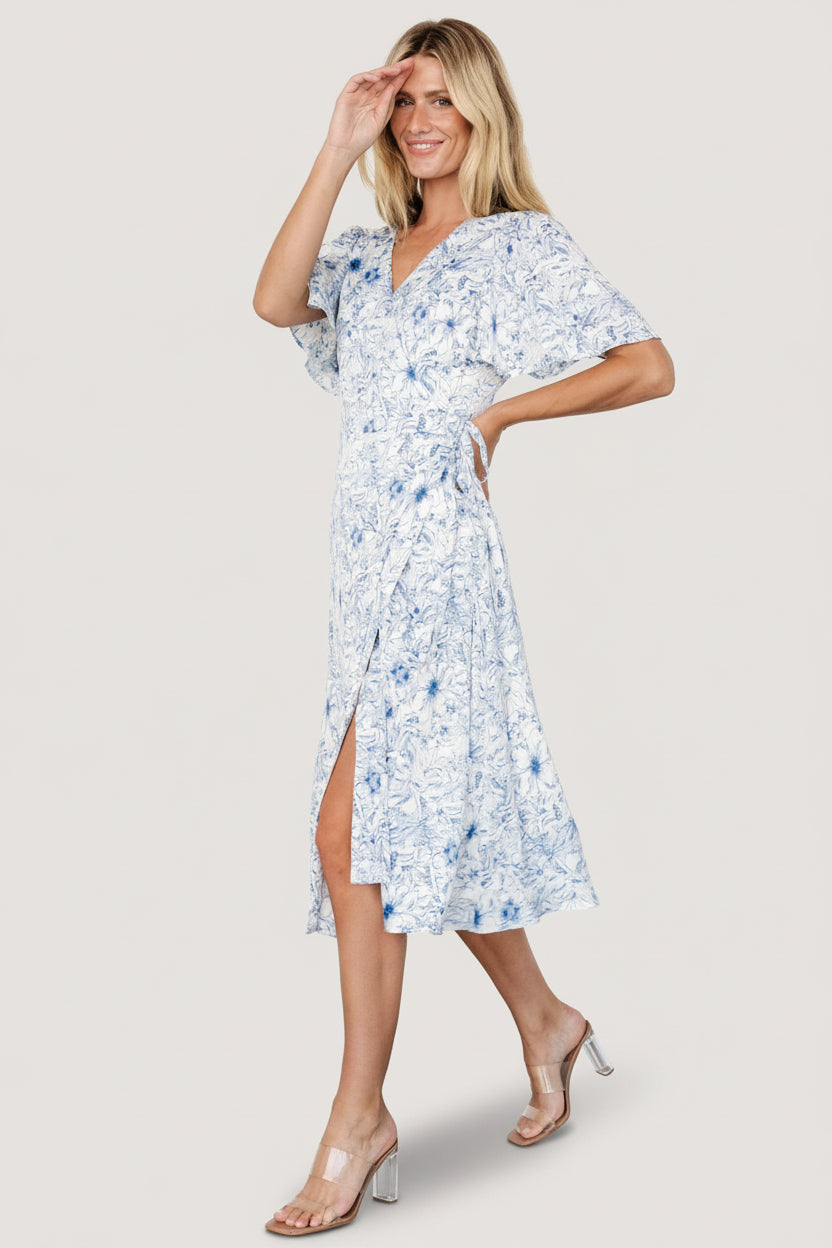 Back view of Amelie Wrap Midi Dress in blue print, showing flutter sleeve detail and midi-length silhouette.