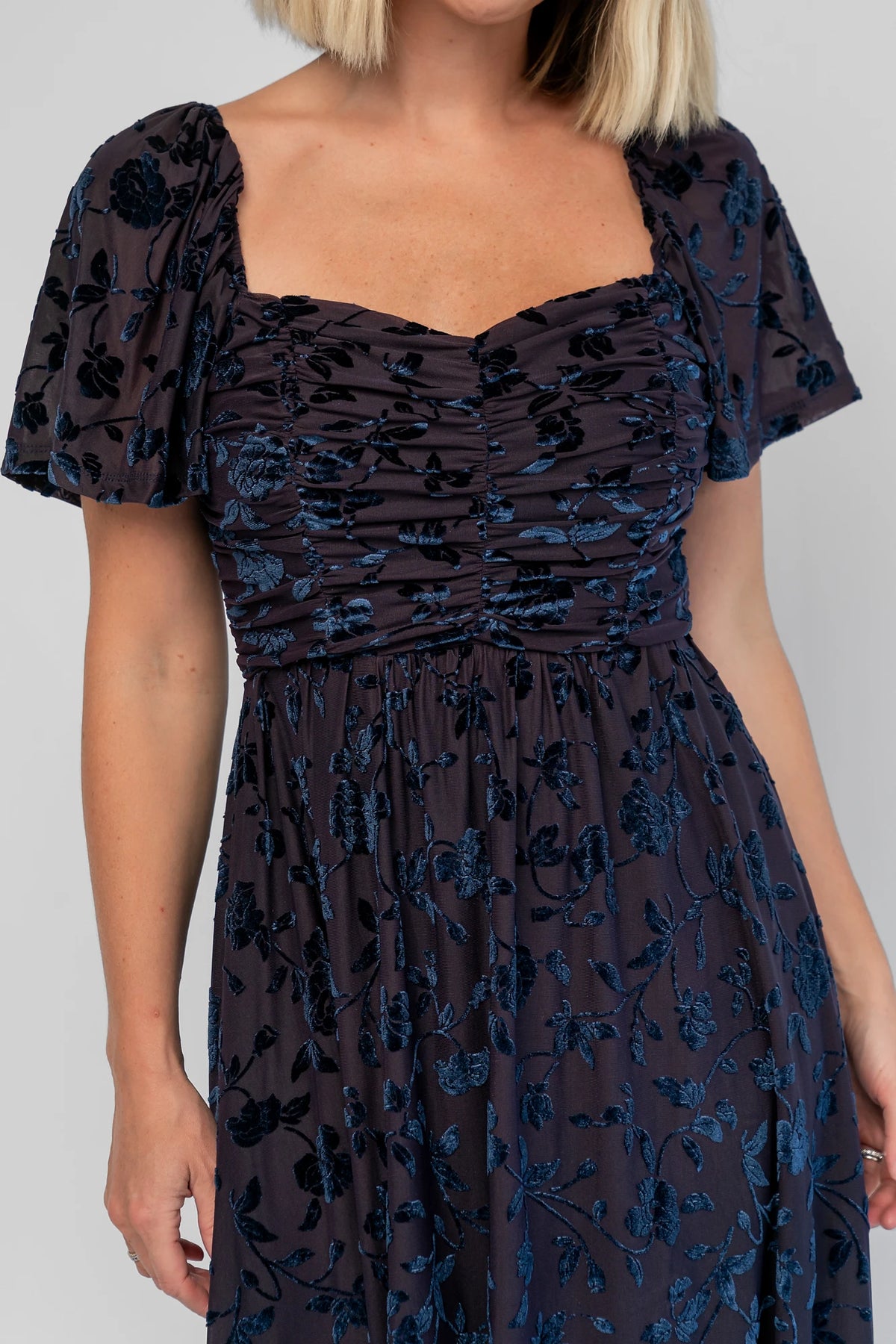 Amoret Midi Dress in Midnight Navy Floral with raised velvet florals, a sweetheart neckline, and flutter sleeves.