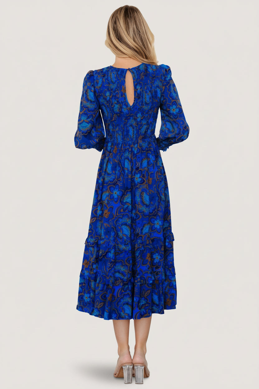 Side view of cobalt floral smocked midi dress with elastic waist and layered ruffle skirt for movement.