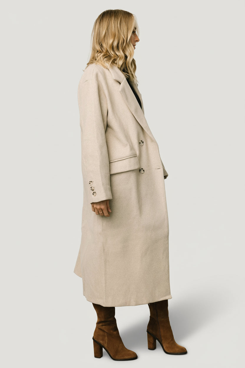 Model wearing Anderson coat in natural, styled open to show layering potential, long length, and neutral color pairing options.