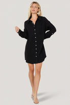 Front view of Andres button shirt dress in black on model, showing collared neckline, full button front, left breast pocket and oversized silhouette.