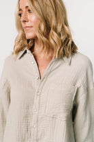 Detail close-up of button-front, cuff buttons, and collar on the light sage oversized shirt dress showing fabric texture and finish.
