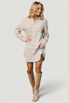 Front view of light sage oversized button shirt dress on model, showing collared neckline and asymmetrical hemline with full button front.