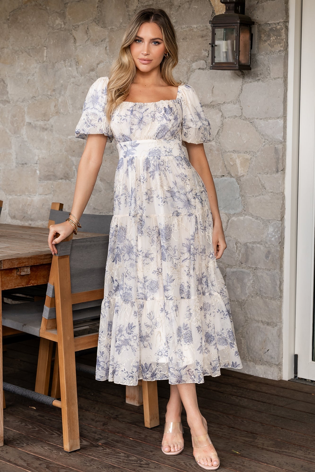 Model wearing cream and slate floral tulle midi dress with hidden pockets and empire waist for a flattering silhouette.