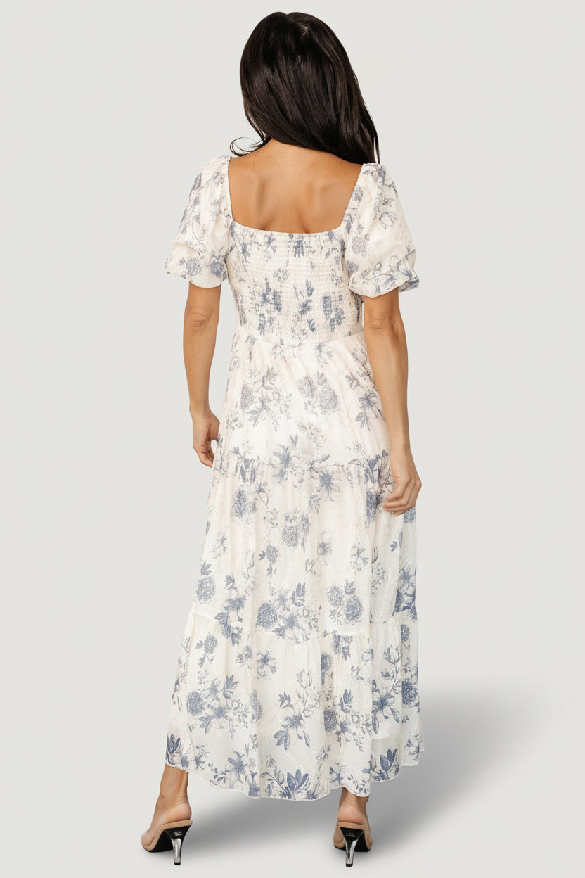 Side profile of cream and slate embroidered tulle midi highlighting balloon sleeve and three-tier flowing skirt.
