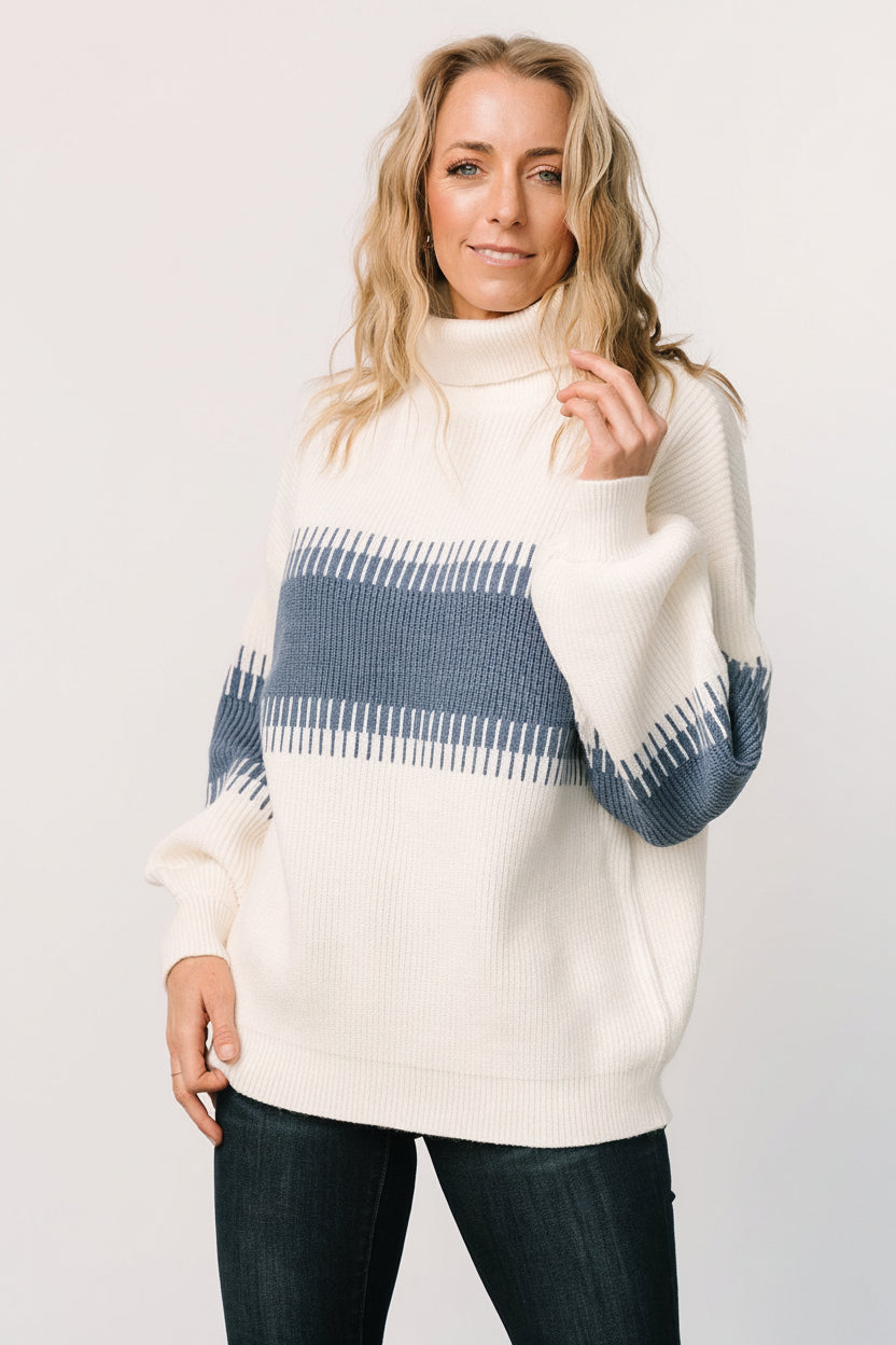 Front view of blue and cream colorblock Antonov turtle neck sweater on a mannequin, showing ribbed hem and long balloon sleeves, high neckline and relaxed fit.