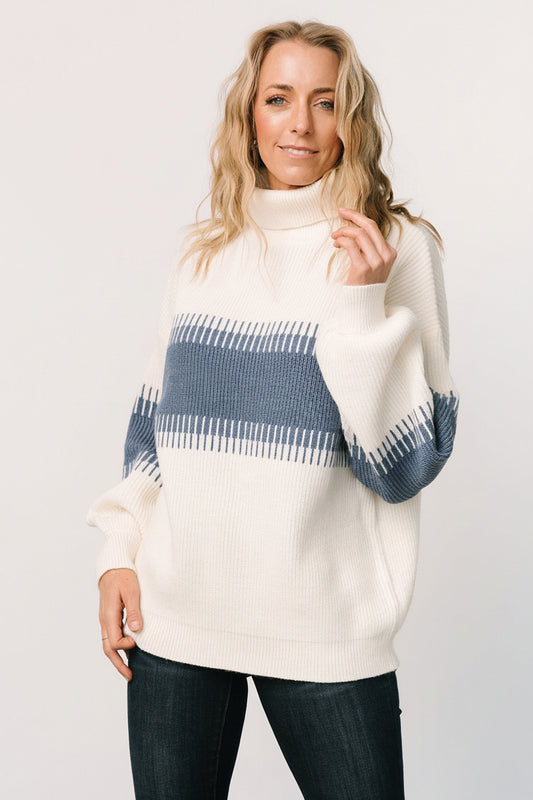 Front view of blue and cream colorblock Antonov turtle neck sweater on a mannequin, showing ribbed hem and long balloon sleeves, high neckline and relaxed fit.