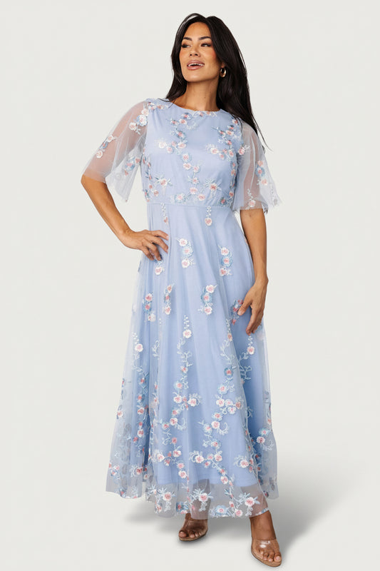 Front view of Arabella light blue tulle maxi dress with blush embroidered floral motifs, round neckline and flowing layered skirt.