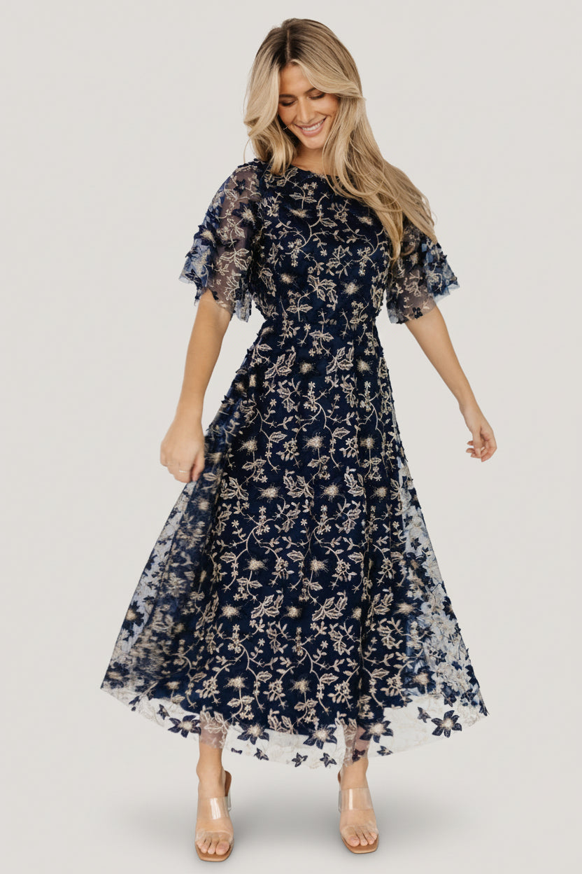 Full-length portrait of navy embroidered tulle maxi dress on model, highlighting silhouette, neckline and skirt volume for events.