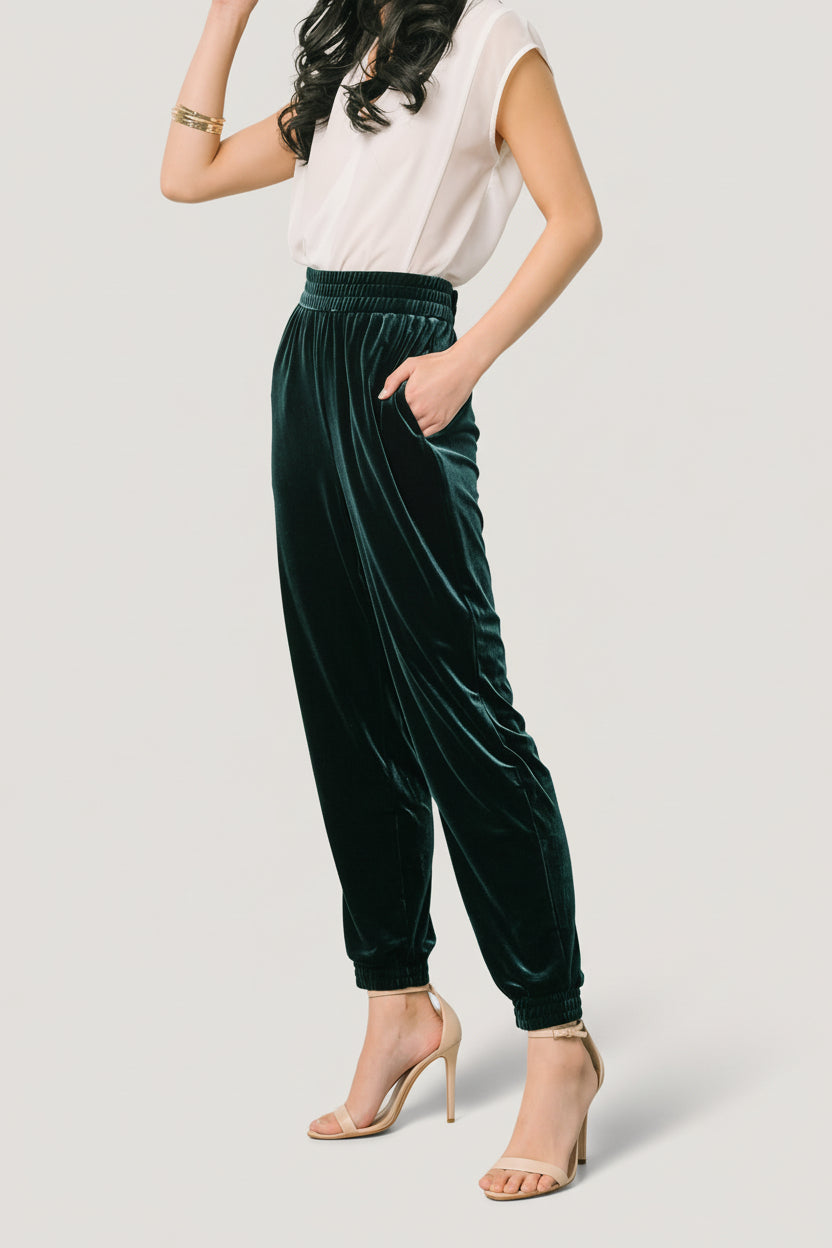 Close-up fabric texture of dark green velvet on Archie jogger pants, displaying soft pile, color depth, and subtle light reflection.