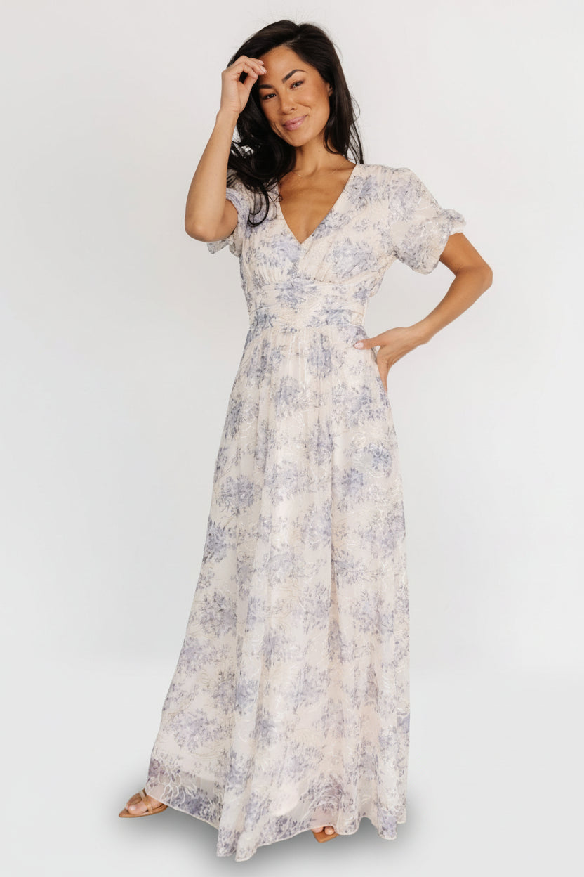 Front view of cream and slate-blue floral maxi dress with gold embroidered accents, V-neck and short puff sleeves, showing full silhouette.