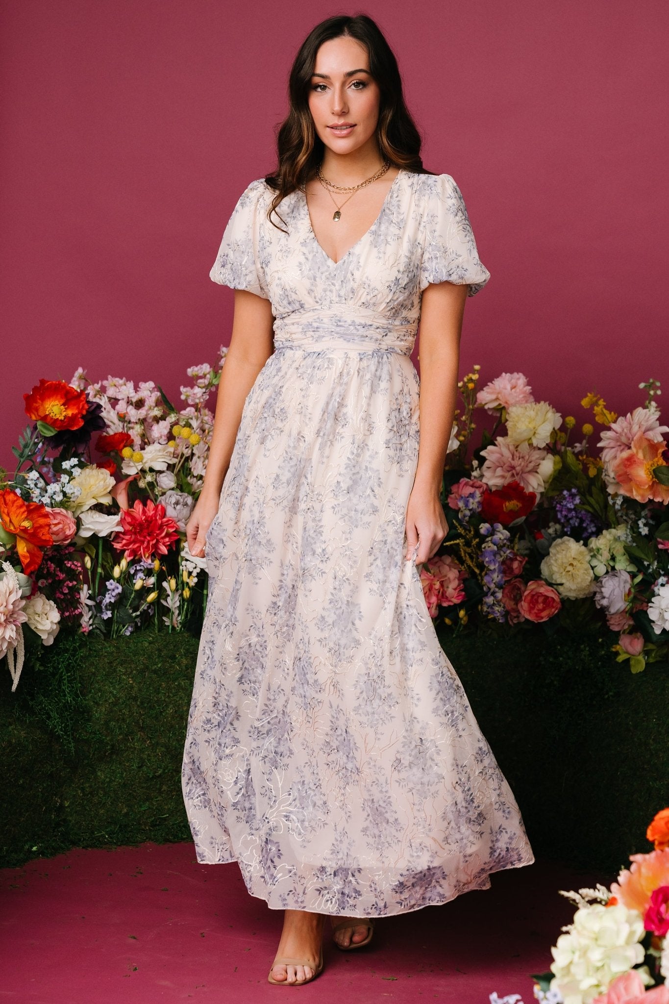 Model wearing cream and blue floral maxi dress, side view highlighting gathered waist, flowing skirt and side pockets.