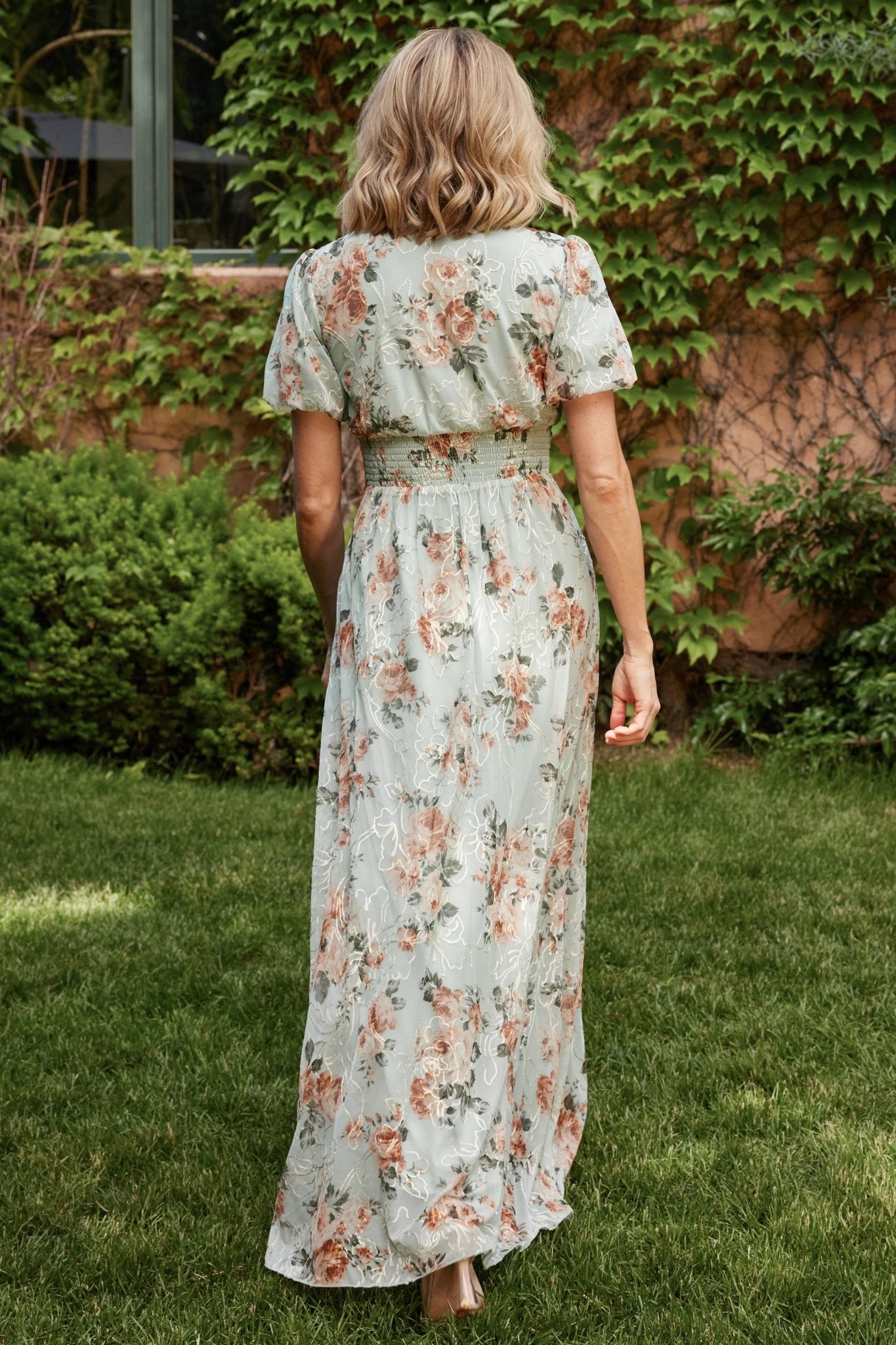 Angled studio shot emphasizing side pockets, waist gathering, and embroidered floral pattern across the flowing maxi skirt for a flattering silhouette.