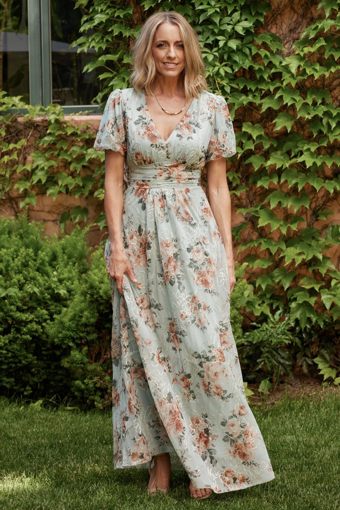 Back view of sage floral maxi dress showing gathered waist, full-length skirt drape, and the subtle sheen of the fully lined interior.