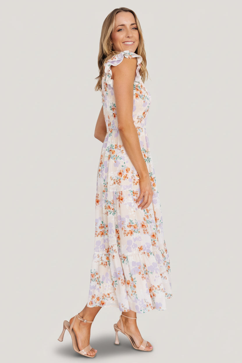 Styled look of cream floral smocked maxi dress worn with casual sandals, showcasing length, pockets, and flowy tiers.