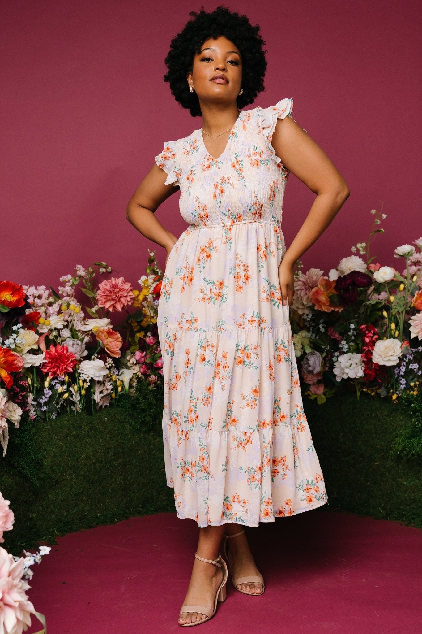 Side view of cream floral smocked maxi dress showing layered ruffle sleeve detail and flowing tiered skirt, model wearing pockets.