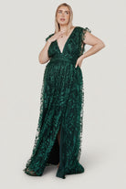 Side view of emerald Arlene Shimmer Gown highlighting tulle sleeve frill, leg slit, and flow of the shimmer tulle overlay across the maxi skirt.