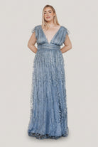 Model shot of the Arlene Shimmer Gown in Winter Blue showcasing sleeve tulle frills, fitted banded waist, and the gown's flowing maxi hem.