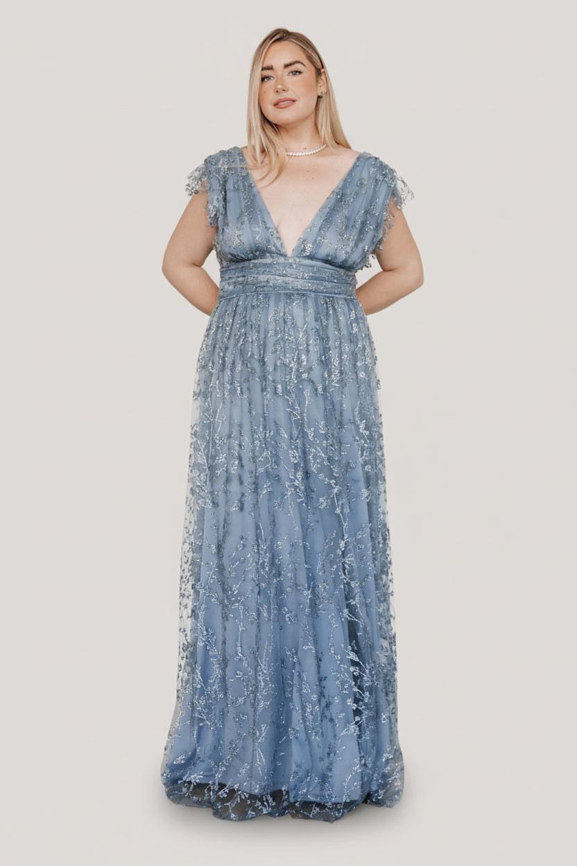 Model shot of the Arlene Shimmer Gown in Winter Blue showcasing sleeve tulle frills, fitted banded waist, and the gown's flowing maxi hem.