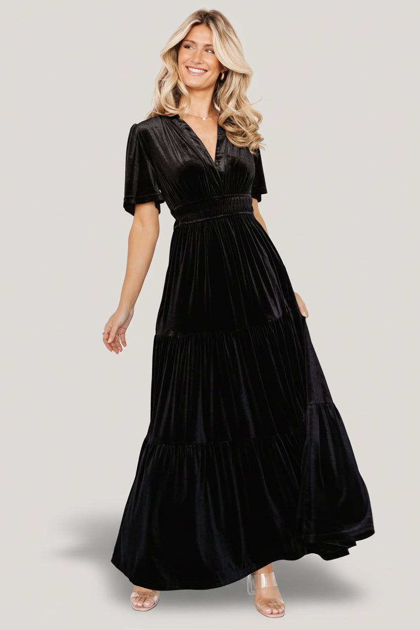 Artemis velvet tiered maxi dress in black on model, front view showing plunging V-neck and short flutter sleeves, full length.