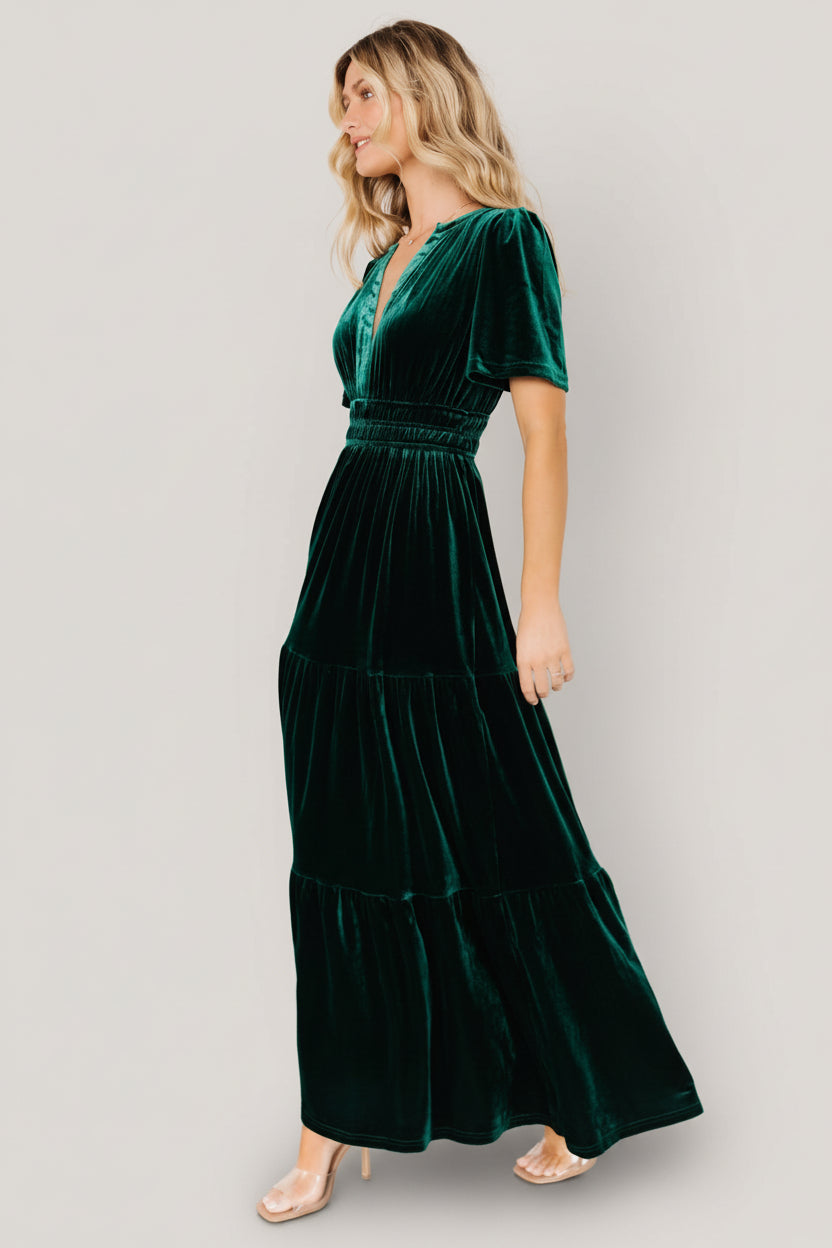 Model wearing emerald Artemis velvet maxi dress walking outdoors, showing skirt tiers, length, and flattering silhouette.