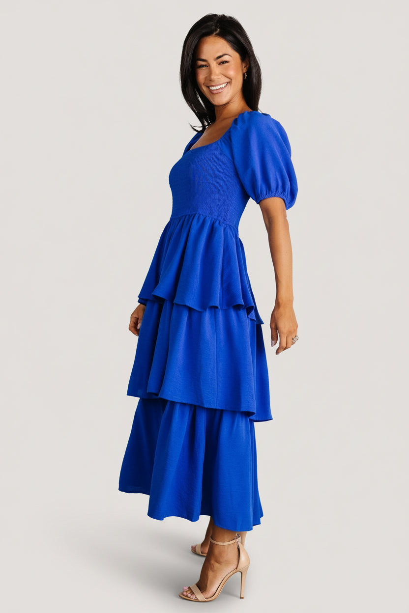 Back view of cobalt midi dress highlighting tiered skirt length, back silhouette, and how the fully lined interior ensures no sheerness.
