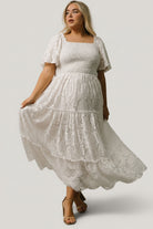 Close-up of lace fabric and smocked bodice on off-white maxi, highlighting lace pattern and neutral inner lining for coverage.