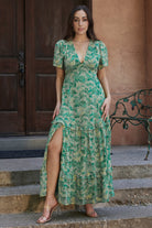 Full-length studio shot of the green floral chiffon maxi dress with short sleeves, flowing tiered skirt and feminine silhouette on model.