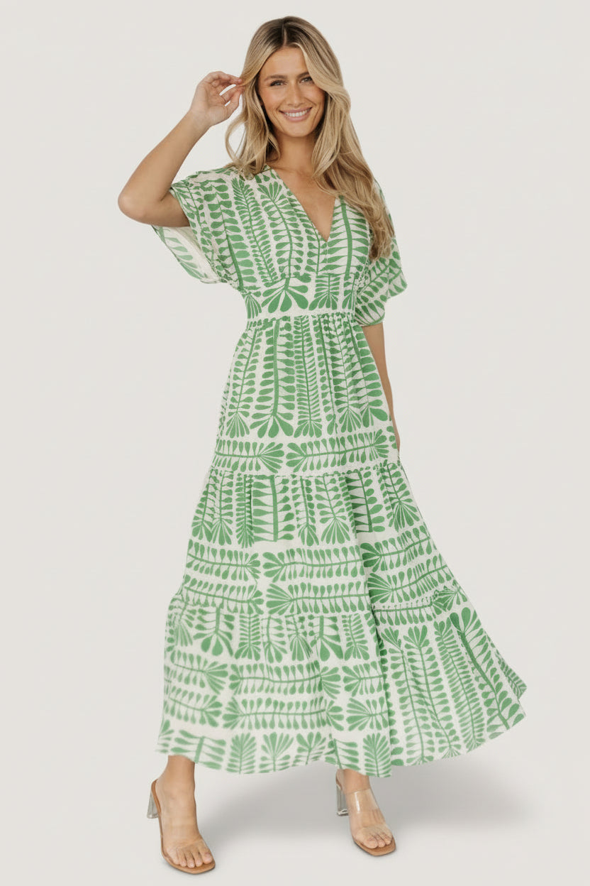 Front view of model wearing Austin Kimono Dress in green floral print with V-neck, smocked elastic back detail and tiered midi skirt, studio shot.