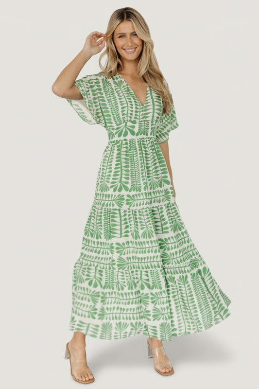 Front view of model wearing Austin Kimono Dress in green floral print with V-neck, smocked elastic back detail and tiered midi skirt, studio shot.