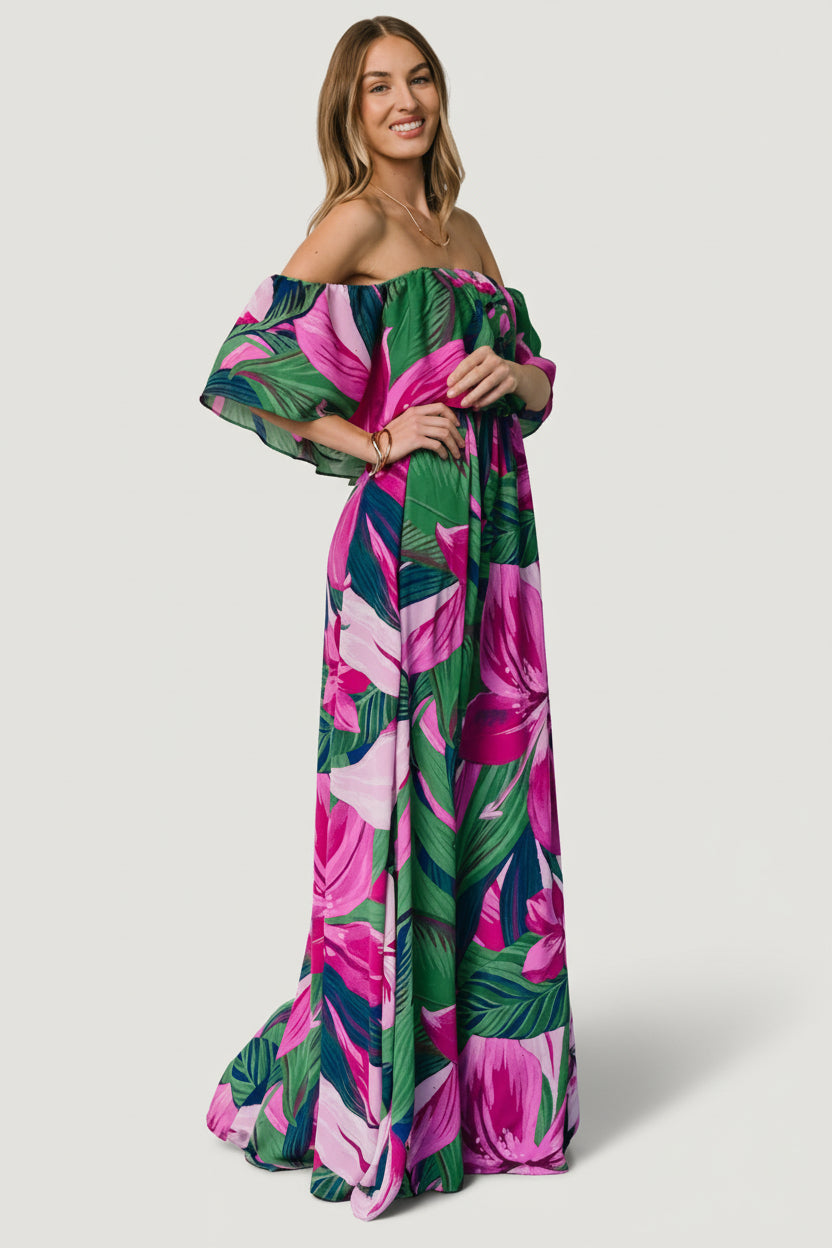 Back view of Azalea off-shoulder maxi dress revealing full lining and gentle drape, patterned with vibrant fuchsia floral motifs on green base.