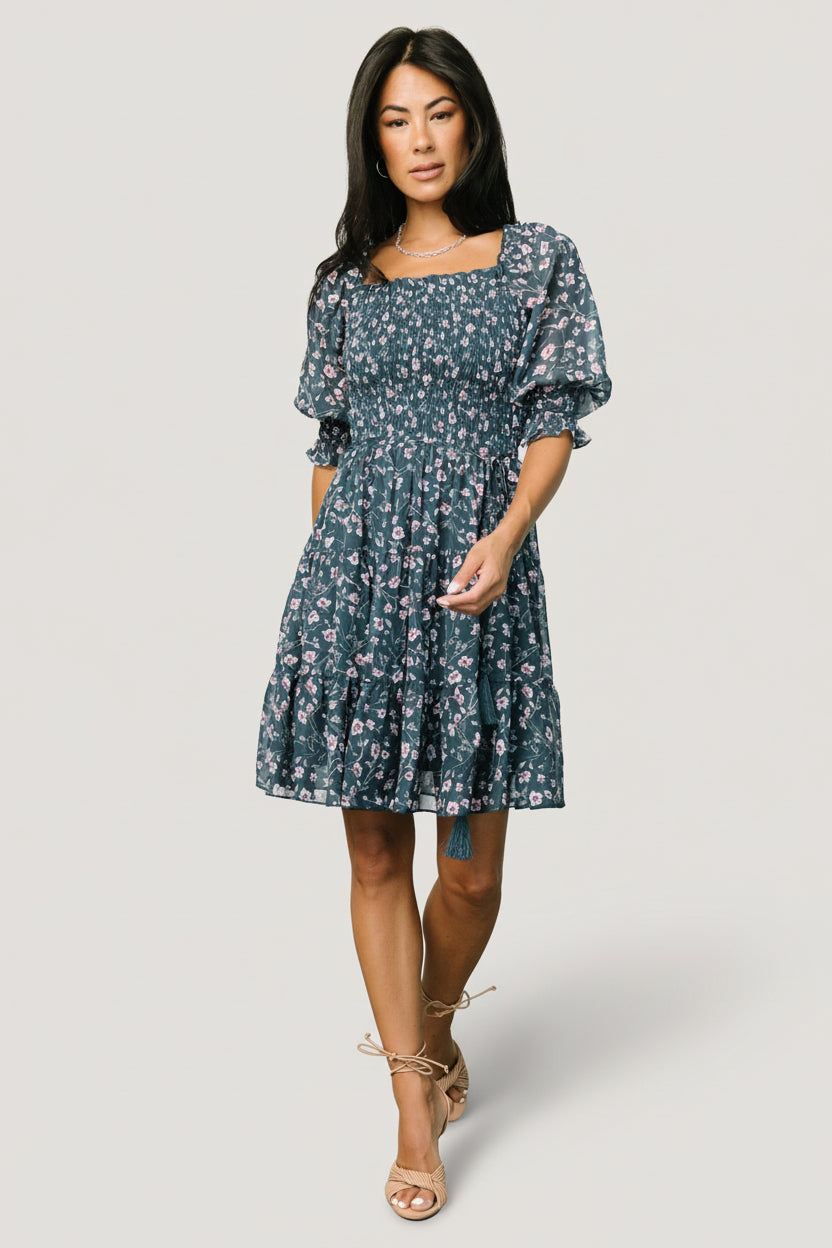 Styled outfit image of Azlyn smocked short dress paired with sandals, showing overall silhouette, length, and movement of the tiered skirt.