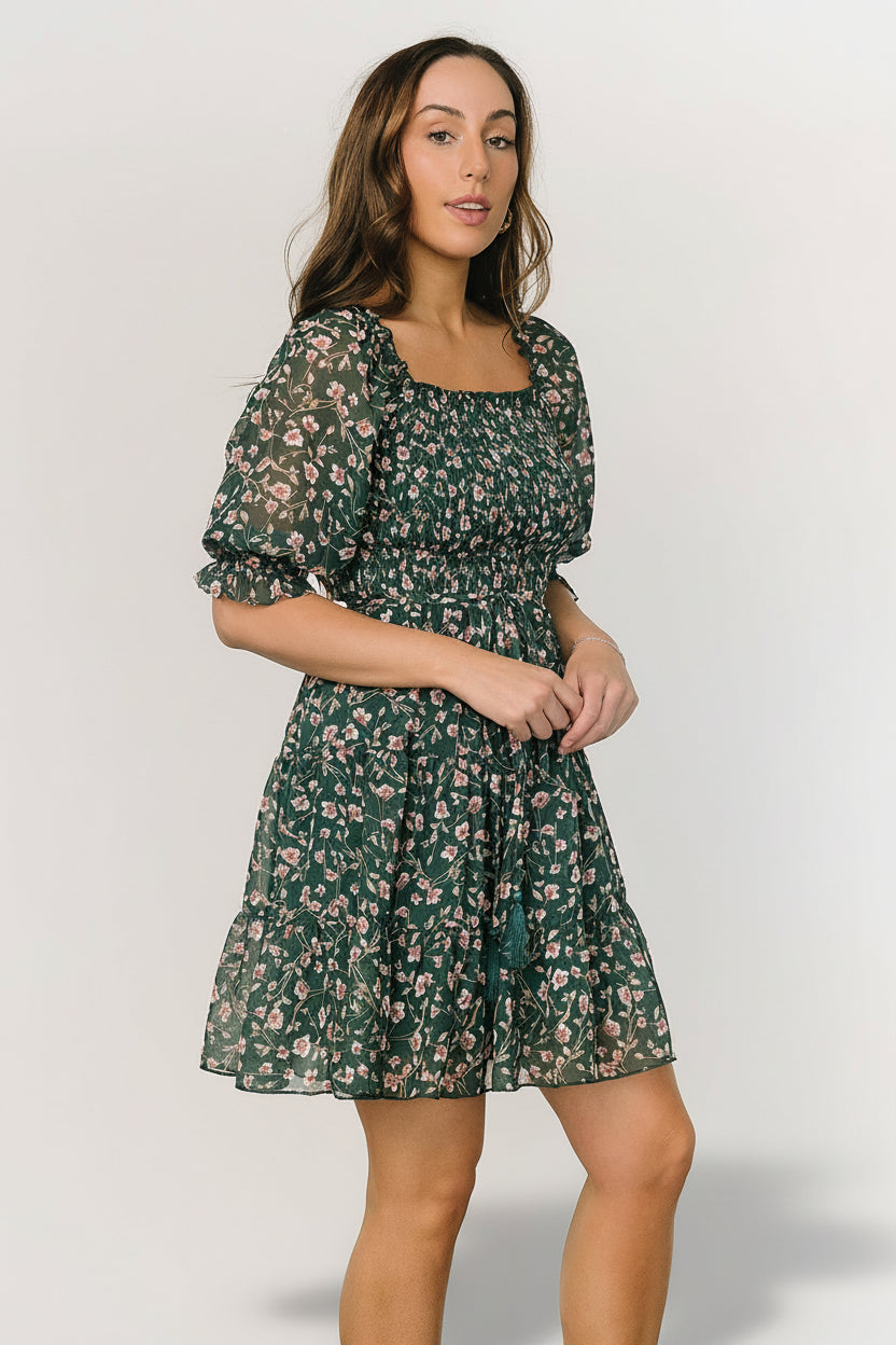 Back and side view of the green floral Azlyn dress showing tiered short skirt, lightweight jacquard chiffon drape, and adjustable waist tie.