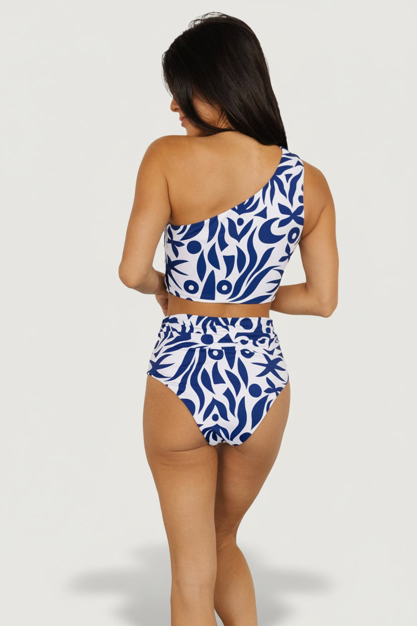 Detail shot of white and navy abstract high-rise bikini bottom showing fabric texture, stitching, and side ruching construction.