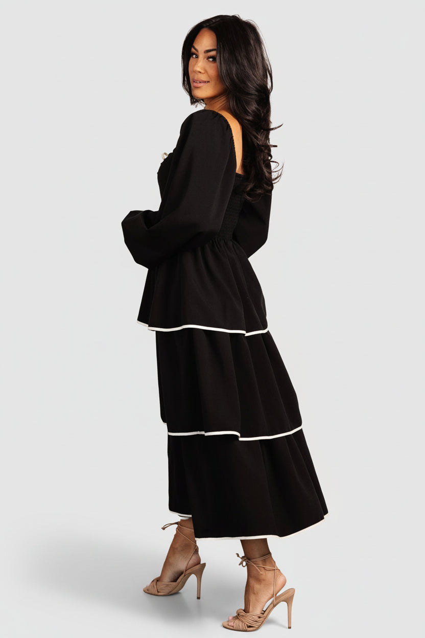 Back view showing smocked back bodice and elastic at shoulder for a flexible fit, with midi skirt tiers flowing below the waist.