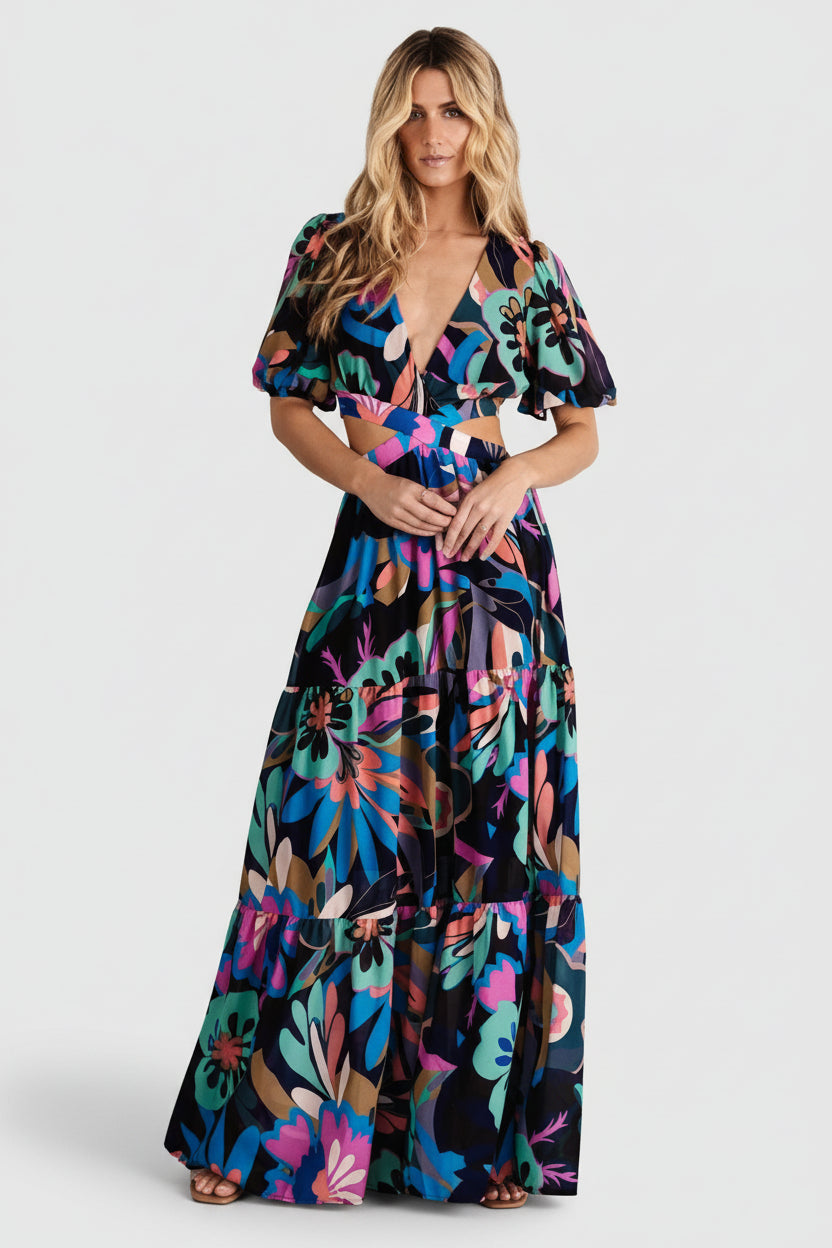 Front view of a tiered chiffon maxi dress in black multicolor retro floral print with deep V-neck, crossover waist, and short puff sleeves.