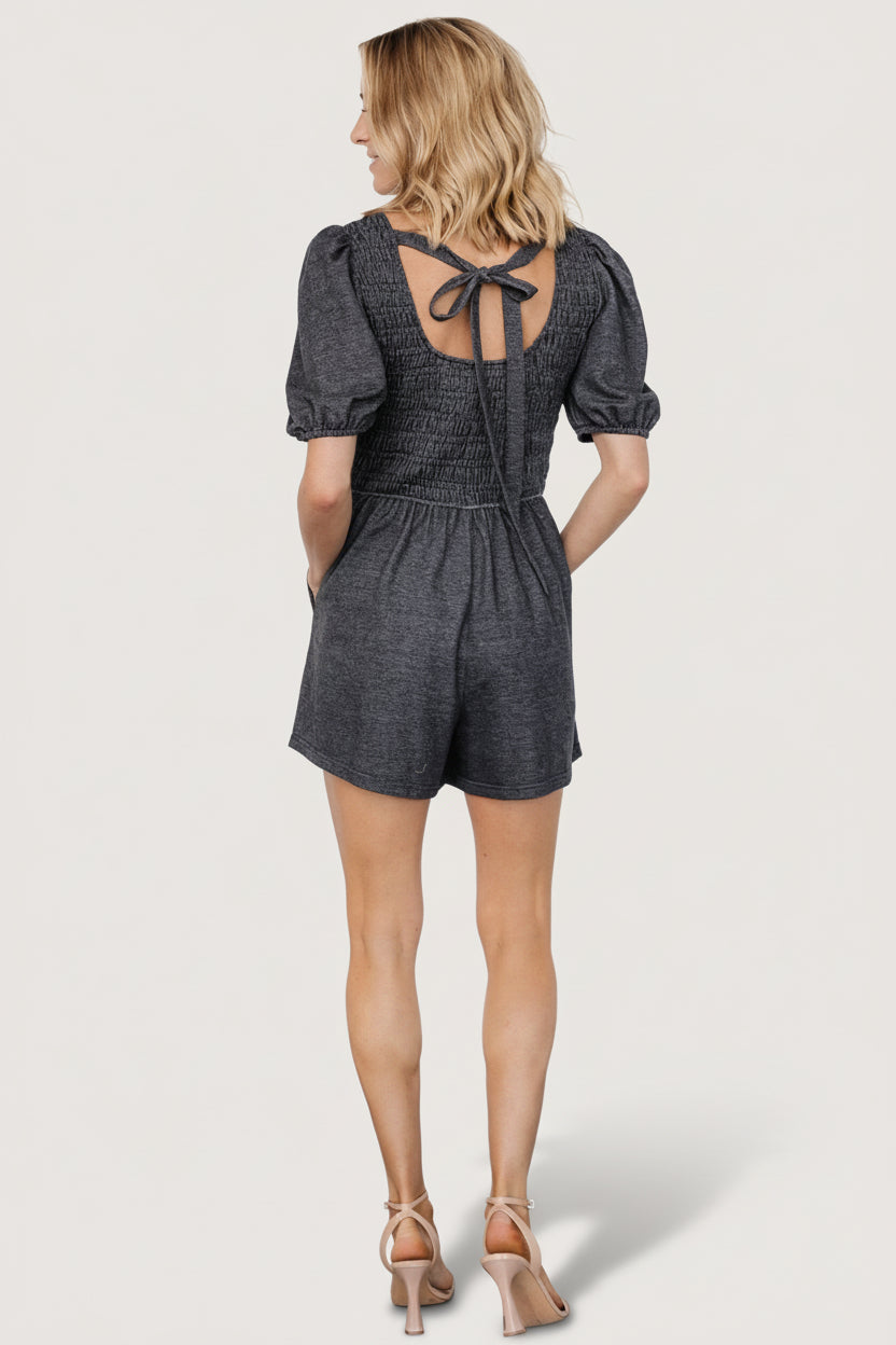 Detail shot of Beaumont Romper heather black showing elastic sleeve cuff, side pocket opening, and the soft drape of the jersey fabric for everyday wear.