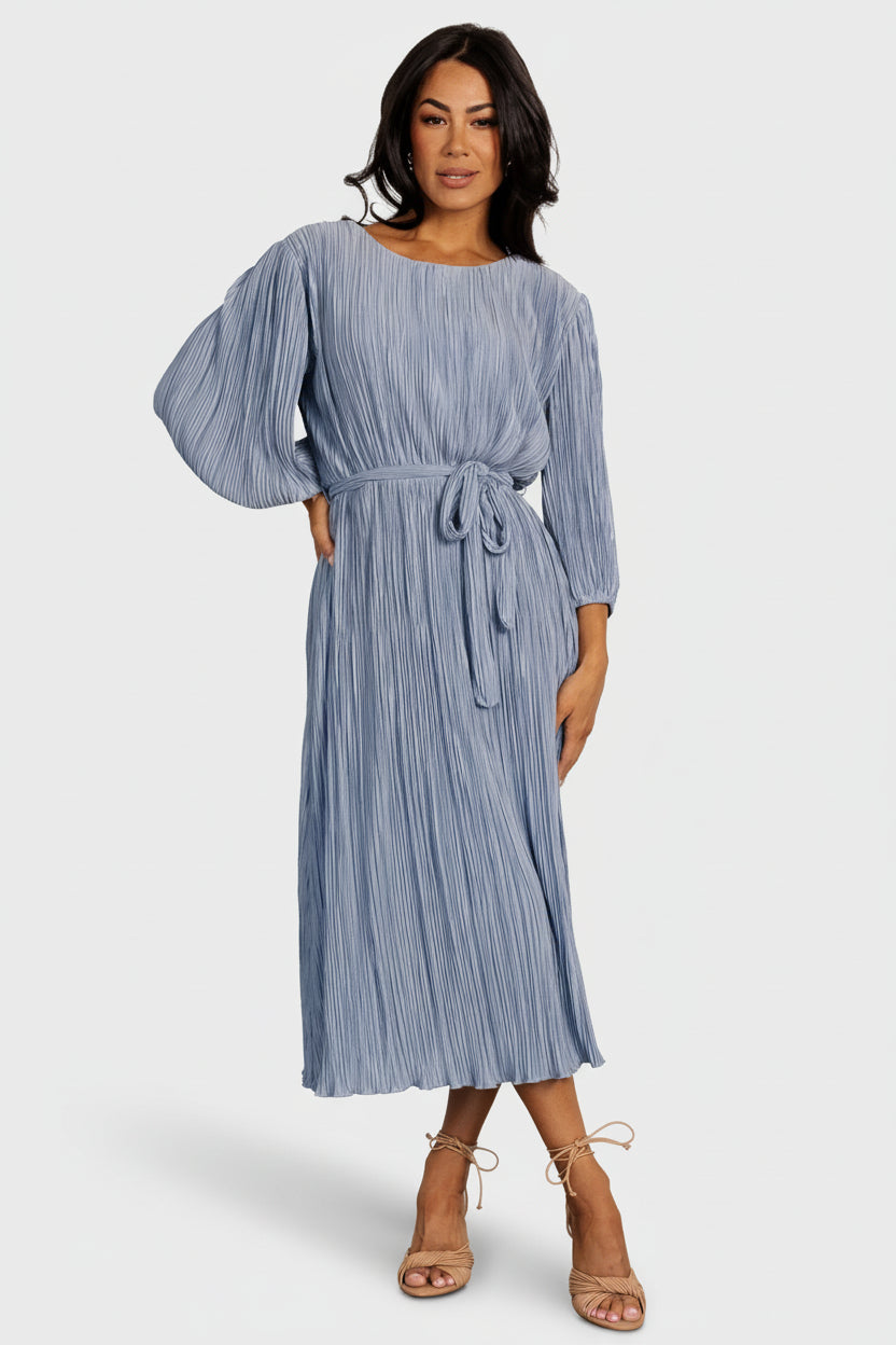 Styled outfit view with the Bethany Pleated Midi Dress in dusty light blue paired with neutral heels, showing fit and movement.
