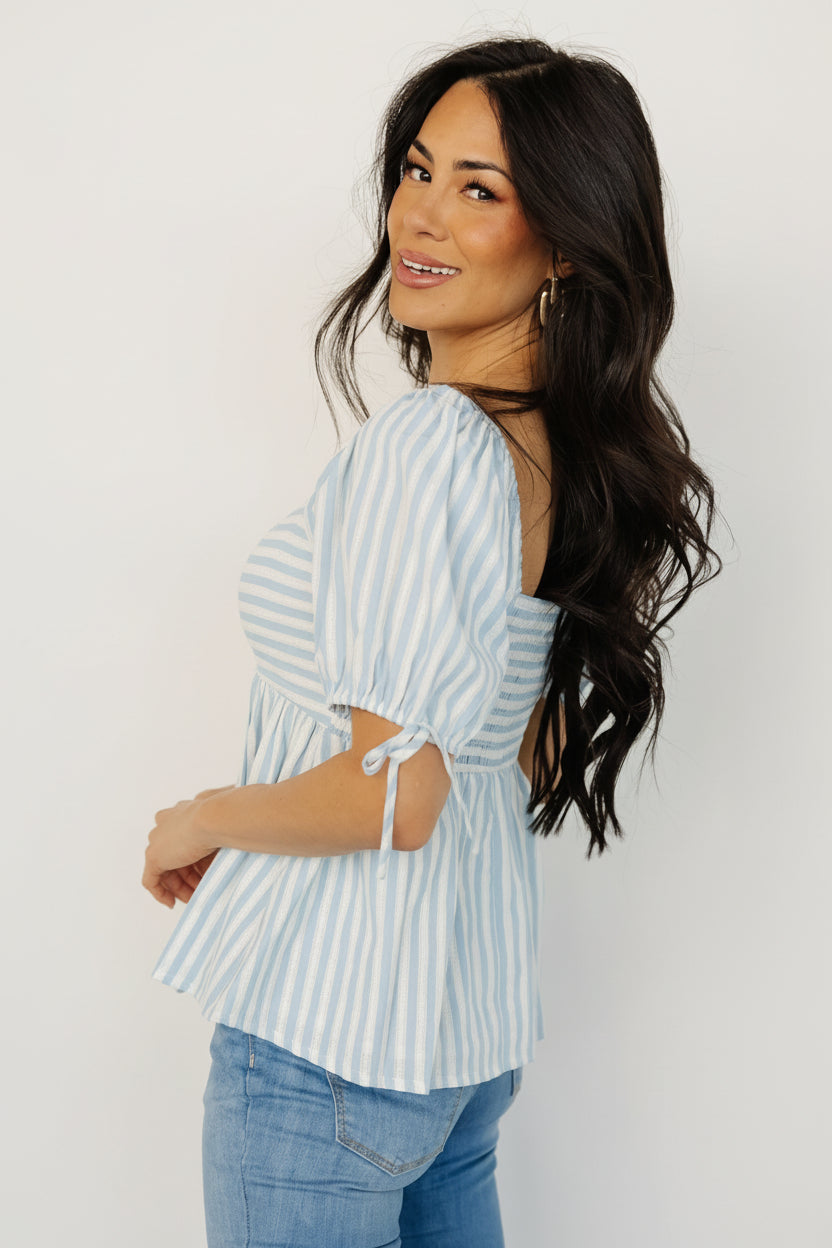 Detail view of short elastic sleeve with decorative tie on the blue-and-white striped top, showing the sleeve finish and unlined drape.