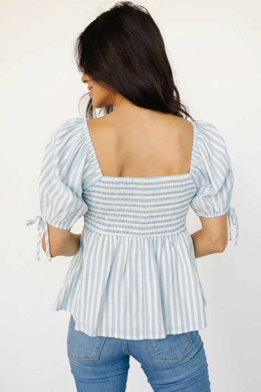 Close-up of embroidered white stripes on the blue peplum top highlighting texture, stitch detail, and cotton-blend fabric weave.