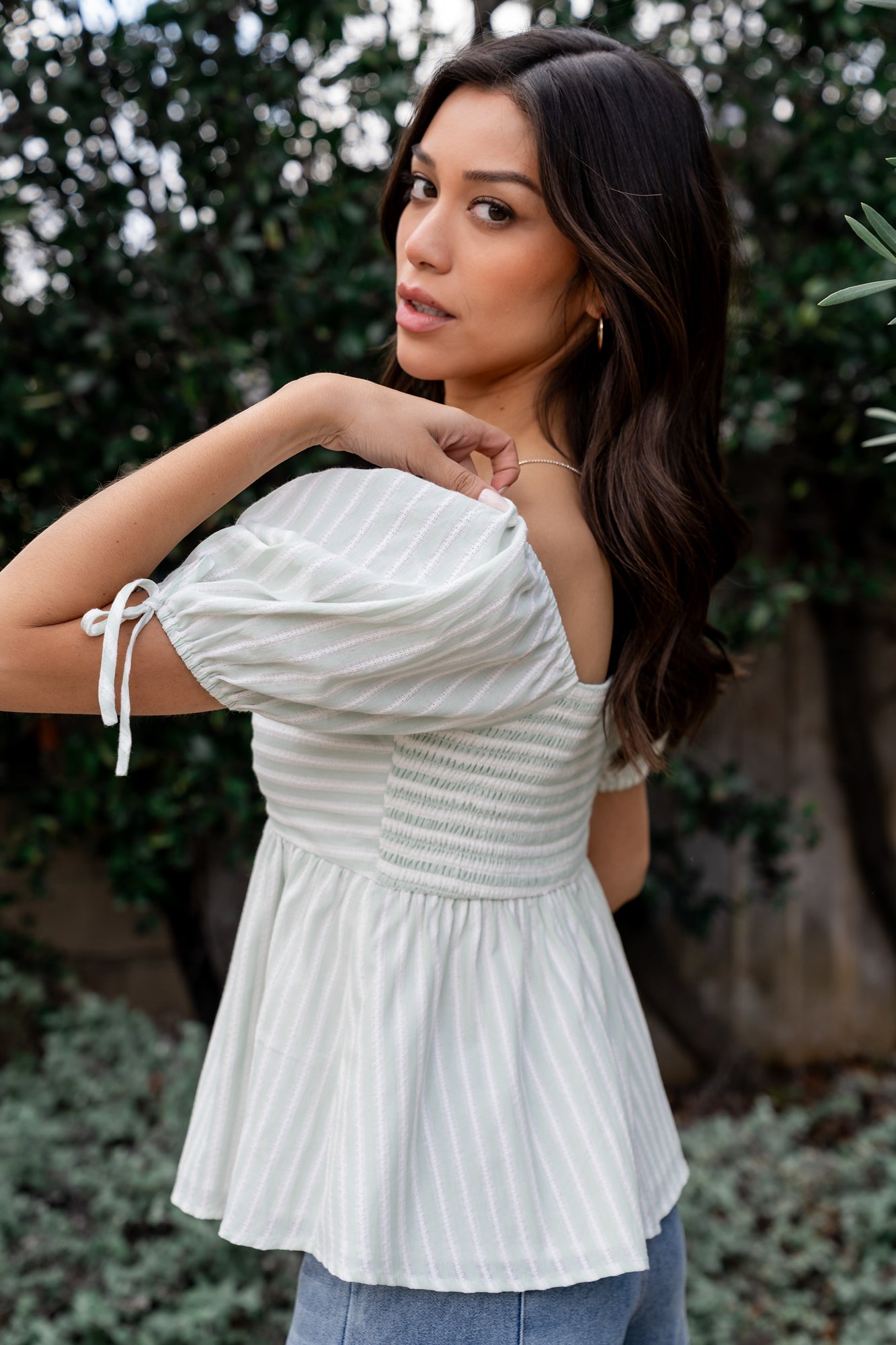Model wearing Betsy Peplum Top paired with mid-rise wide leg jeans, showing relaxed silhouette and peplum detail.