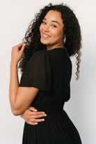 Back view of the black Birdie Maxi Dress with soft chiffon drape and gathered smocked waist creating natural movement.