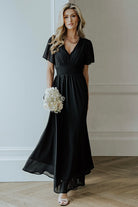 Three-quarter view of black Birdie Maxi Dress showing drape of chiffon skirt, V-neck bodice, and smocked waistline for a flattering silhouette.