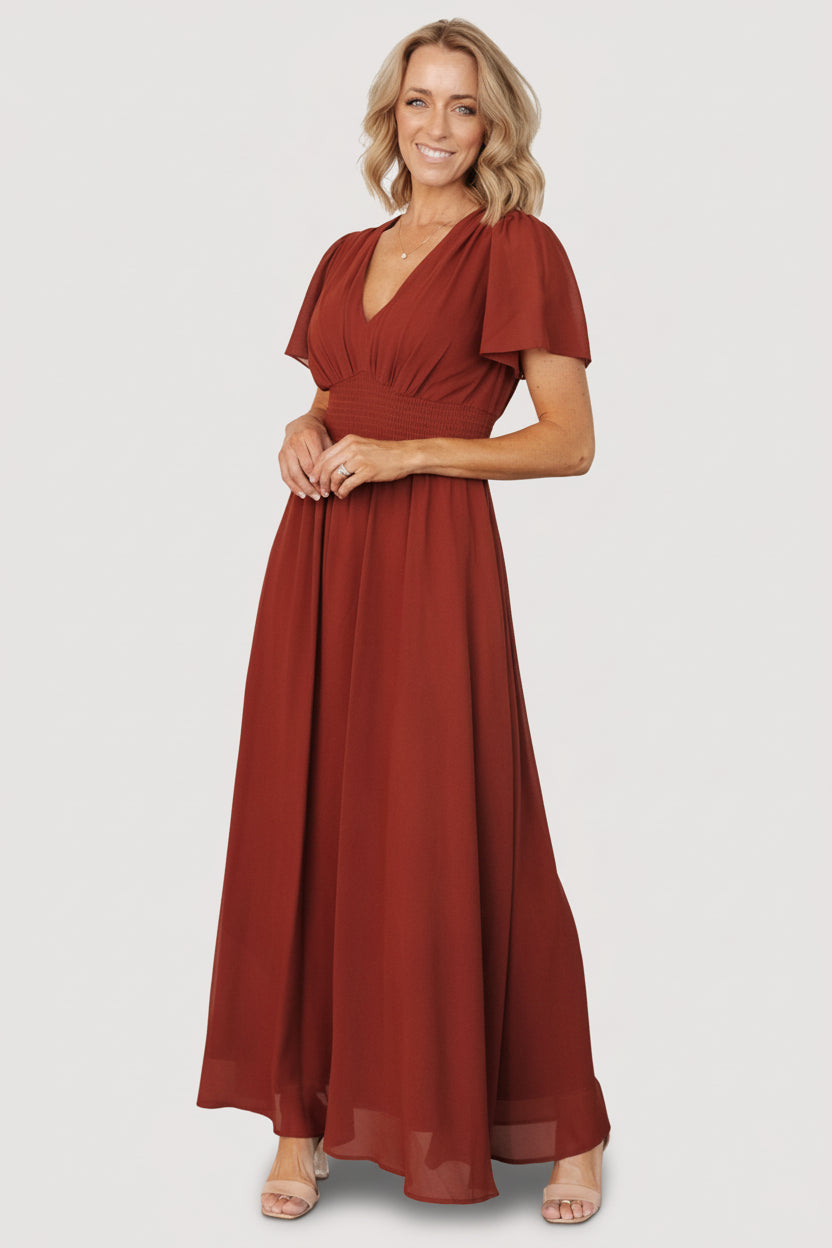 Front view of the Birdie Maxi Dress in cinnamon chiffon on a model, showing V-neckline, short flutter sleeves, and a smocked waist for shape and movement.