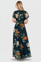 Model seated in deep topaz floral maxi dress demonstrating movement of lightweight chiffon and lined skirt.