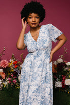 Detail of short flutter sleeve and V-neckline in off-white chiffon with delicate blue floral pattern.