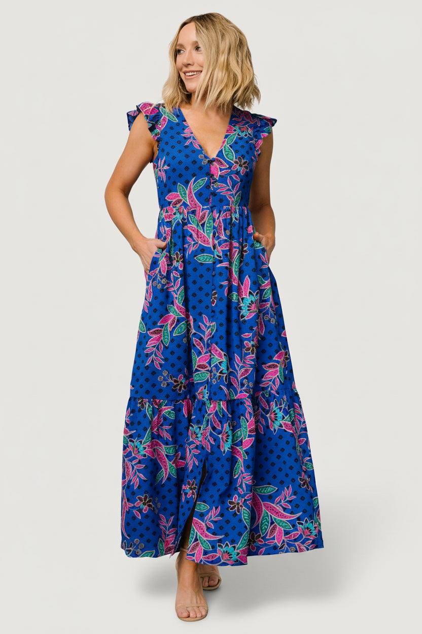 Front view of indigo multi-print tiered chiffon maxi dress with V-neck, button-front, flutter sleeves, and side pockets.